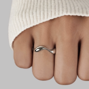 Zilveren egale ring met een twist in. De ring is getoond op de ringvinger van de hand.