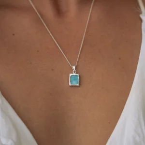 een zilveren ketting met een bedel van blauw zeeglas