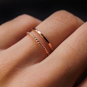 Rosé goude ringenset met 2 ringen, getoond aan ringvinger. De bovenste ring is egaal en de onderste is geribbeld.
